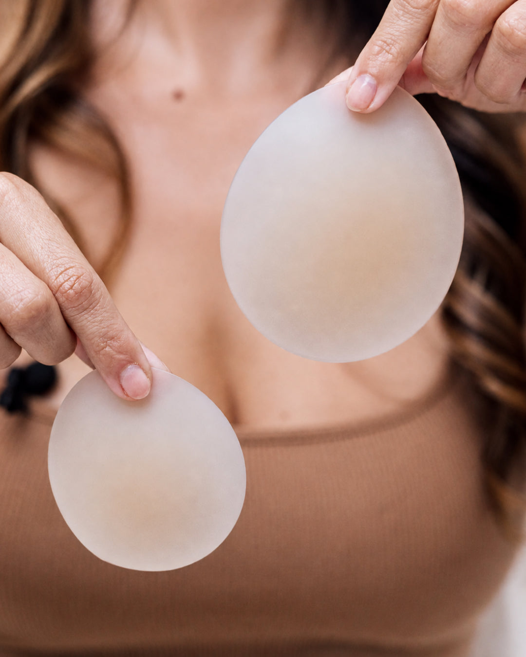 Hands holding two Velomora silicone nipple covers