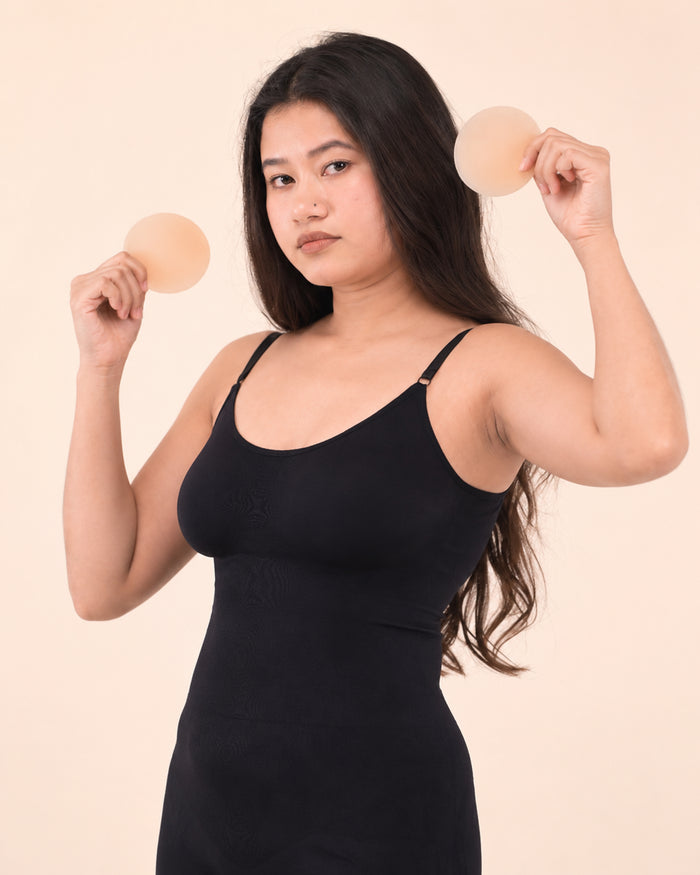 Model in the black bodysuit holding a pair of nipple covers